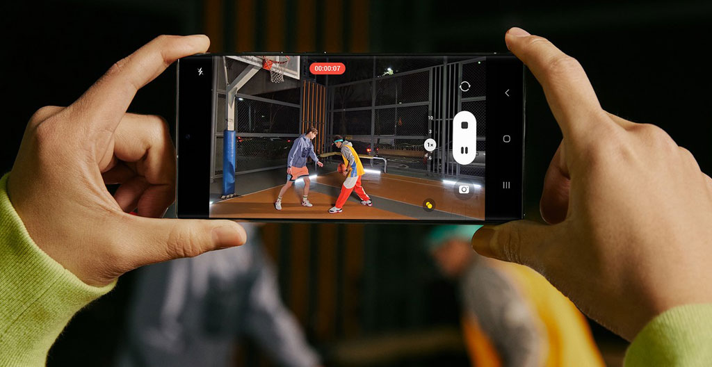 Personne assise dans un transport en commun regardant son téléphone avec une expression concentrée, lumière naturelle de fenêtre